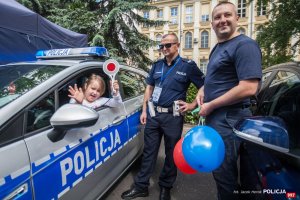 Dziecko w radiowozie policyjnym w towarzystwie dwóch policjantów