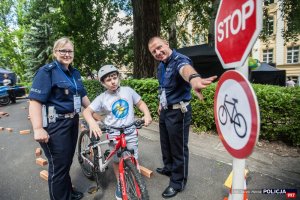 Dziecko na rowerze przy znaku drogowym STOP w towarzystwie policjantów Ruchu Drogowego Komendy Stołecznej Policji