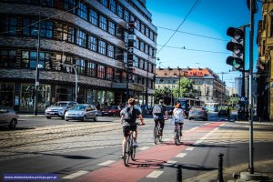 Rowerzyści jadący rowerami pasem ruchu dla rowerów koło Renomy we Wrocławiu