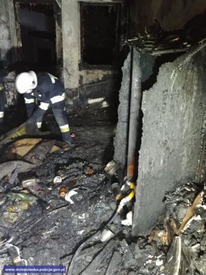 Strażak przeszukuje pomieszczenia po pożarze