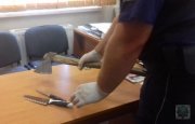 policjant ogląda zabezpieczone noże i siekierę