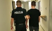 policjant prowadzi zatrzymanego mężczyznę do aresztu