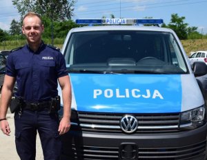 st. post. Bartosz Czech z Komendy Powiatowej Policji w Krakowie stoi przed radiowozem policyjnym