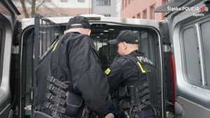 dwaj policjanci zamykają tylne drzwi w busie policyjnym