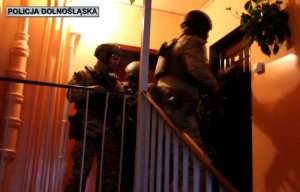 Policjanci pod drzwiami do mieszkania podejrzanego