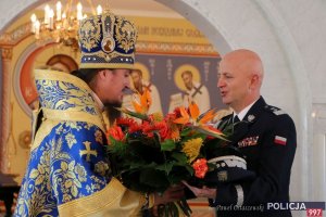 Komendant główny Jarosław Szymczyk wręcza wiązankę kwiatów arcybiskupowi Jerzemu