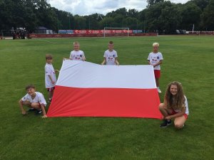 dzieci na murawie prezentują flagę Polski