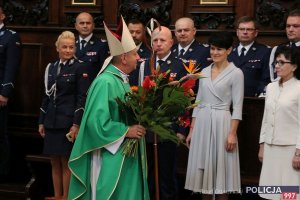Bp Józef Guzdek idzie z kwiatami w stronę minister Elżbiety Witek