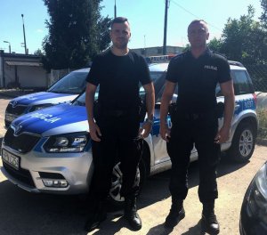 Na zdjęciu widoczny jest sierż. Marcin Kaszubowski i st. post. Łukasz Filip. W tle znajduje się radiowóz policyjny.
