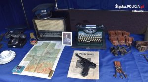 Zdjęcie przedstawia stolik z wystawionymi eksponatami Policji Województwa Śląskiego. Po środku leży pistolet.