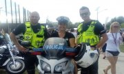 Jedna z uczestniczek festynu na policyjnym motocyklu w asyście policjantów