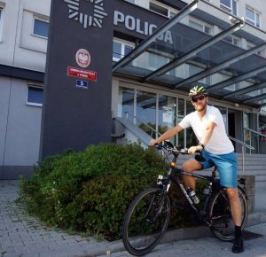 Asp. Artur Wyciszkiewicz na rowerze przed budynkiem komendy policji