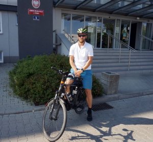 Asp. Artur Wyciszkiewicz na rowerze przed budynkiem komendy policji