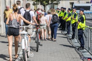 Plac Piłsudskiego - policjanci stoją w szeregu przy barierkach oraz grupa ludzi z roweramiudająca się na uroczystość