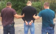 policjanci prowadzą zatrzymanego zakutego w kajdanki