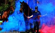 Policjantka prowadzi konia - wokół dym powstały na skutek wystrzelenia rac dymnych