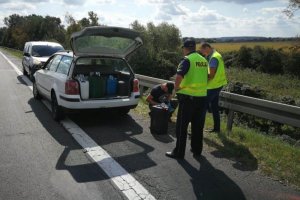 Policjanci wykonują czynności przy zatrzymanym samochodzie z kradzionym paliwem