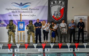 Zdjęcie przedstawia gości zgromadzonych na otwarciu zawodów m.in. Zastępca Komendanta Głównego Kamil Bracha, wdowę po zmarłym Policjancie Annę Lejko  z dziećmi oraz dowódzcę BOA Dariusza Ziębe.