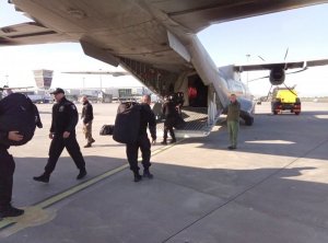 policjanci ładują sprzęt na pokład samolotu transportowego