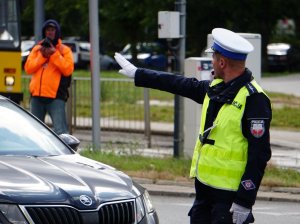 policjant gestem ręki zatrzymuje samochód