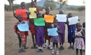 Dzieci z Tanzanii z kartami w ręku a na nich napisami po angielsku