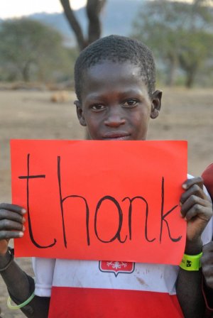 Chłopiec z Tanzanii trzyma w ręce kartkę z napisem thank&quot;&gt;