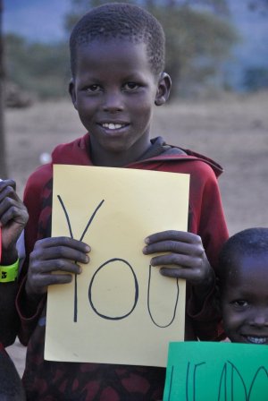 Chłopiec z Tanzanii trzyma w ręce kartkę z napisem You&quot;&gt;