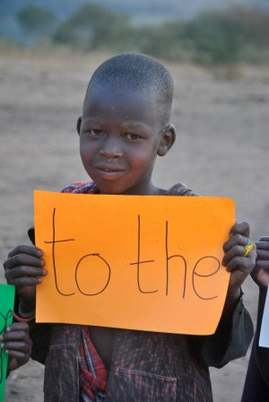 Chłopiec z Tanzanii trzyma w ręce kartkę z napisem to the&quot;&gt;