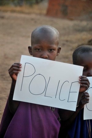 Chłopiec z Tanzanii trzyma w ręce kartkę z napisem Police&quot;&gt;