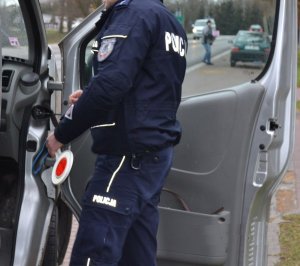 policjant ruchu drogowego z lizakiem w ręku kontroluje kierowcę