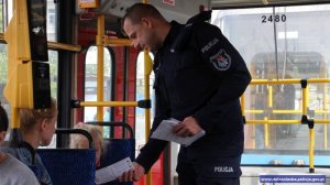 Policjant przekazuje w tramwaju ulotkę dziewczynce