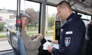 Policjant przekazuje w tramwaju ulotki profilaktyczne seniorowi