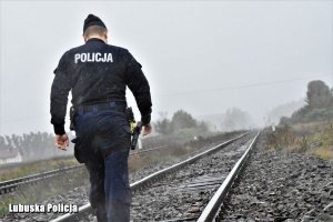 policjant w deszczu idzie po torach