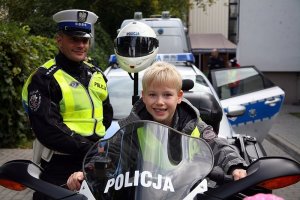 chłopiec na motocyklu obok stoi policjant
