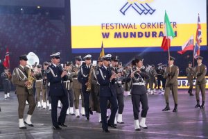 orkiestra wojskowa - po prawej stronie flagowi z barwami państw układu NATO