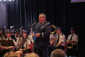 komendant wojewódzki policji w Krakowie przemawia do mikrofonu, w tle orkiestra