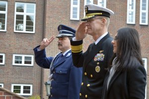 Wiceadmirał i komendant szkoły salutują przed tablicą.