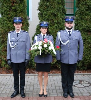 dwaj policjanci i policjantka trzymająca wiązanką kwiatów