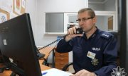 Policjant siedzący przed komputerem rozmawiający przez  telefon