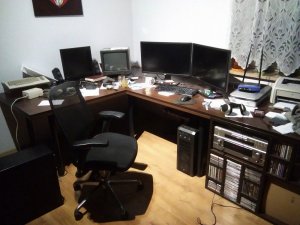 wnętrze mieszkania na stołach wokół ścian znajdują się monitory komputerów, myszki komputerowe, klawiatury, pod stołami stoją komputery