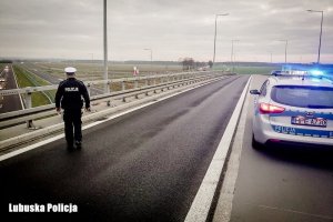 radiowóz policyjny i policjant na drodze
