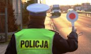 Policjant drogówki  macha  lizakiem policyjnym aby zatrzymać jadący samochód
