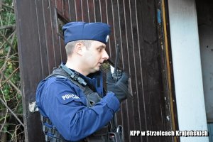 policjant w trakcie sprawdzania pustostanu z radiostacją w ręku