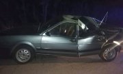 srebrny samochód osobowy  stojący na drodze  z uszkodzona karoserią, pęknięta na pół