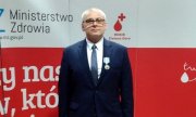 policjant z Gubina odznaczony medalem Ministra Zdrowia stoi na tle biało-czerwonego baneru