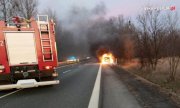 Pojazd straży pożarnej na tle palącego się samochodu