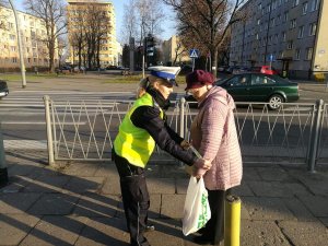 policjantka ruchu drogowego rozdaje odblaski seniorom z okazji dnia babci i dziadka