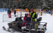 policjant wraz z dziećmi pozują do zdjęcia na specjalnym pojeździe przystosowanym do jazdy na stokach narciarskich