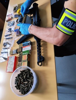 zabezpieczona amunicja, pistolet i rewolwer oraz policjant trzymający zabezpieczony przedmiot