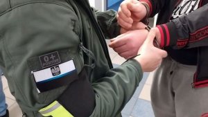 Policjant zakłada kajdanki zatrzymanemu mężczyźnie
